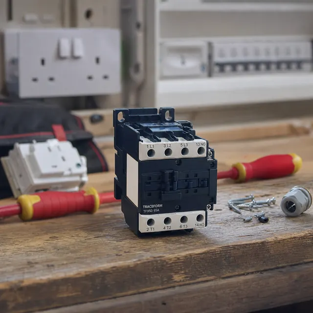 Electrical contactor and screwdrivers on a bench beside a socket
