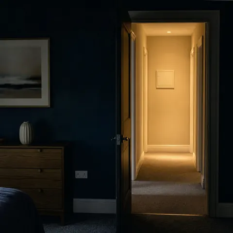 Dark hallway with light spilling from one open doorway
