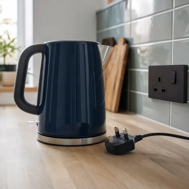 Navy kettle plugged into a socket on a tiled kitchen wall