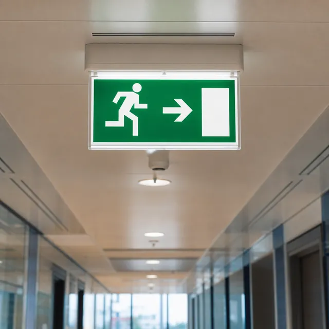 Illuminated green emergency exit sign in a commercial corridor