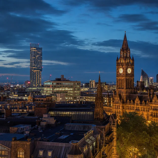 Manchester skyline at night with the town hall clock tower lit up